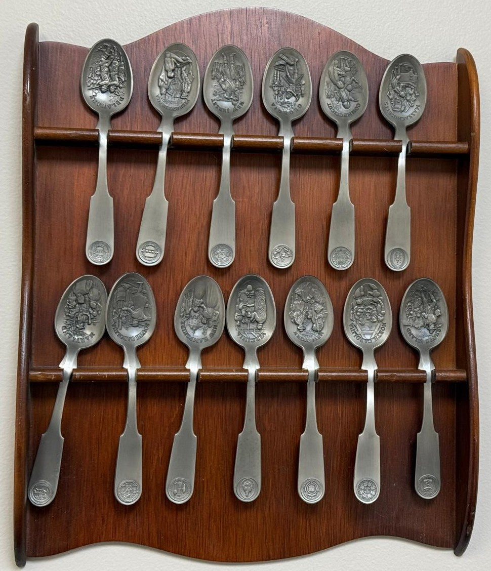 Franklin Mint 13 Original American Colonies pewter spoons with a wooden display rack.